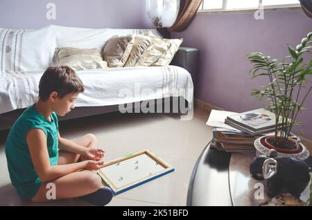 Bambino che gioca a palle di vetro a casa. Concetto di casa felice. Salvador, Bahia, Brasile. Foto Stock