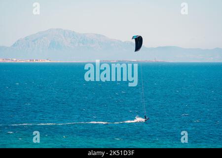Angolo alto di persone che fanno kite surf su acqua turchese ondulazione di mare con montagne sfocate Foto Stock
