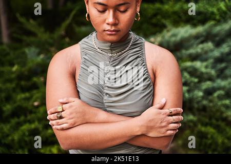 Giovane filippino da sogno non binary man con orecchino abbracciandosi con amore in piedi con gli occhi chiusi in giardino verde Foto Stock