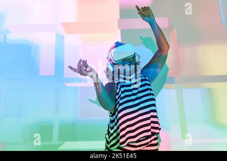Donna anziana in occhiali e cuffie VR per esplorare il cyberspazio Foto Stock