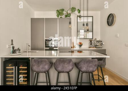 Moderno design interno casa con cucina isola con bancone e sgabelli sotto  il cofano in spazioso appartamento open space in stile loft Foto stock -  Alamy