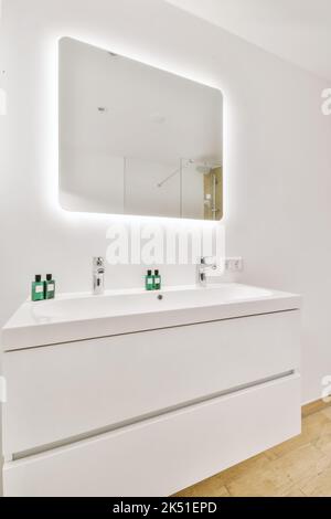 Interno di un lavandino accanto ad uno specchio con pareti bianche con terreno scuro Foto Stock