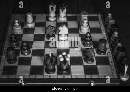 Foto dall'alto in bianco e nero di una scacchiera di legno con alcuni pezzi su di essa Foto Stock