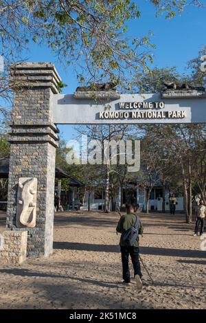 Indonesia, Isola di Komodo, Parco Nazionale di Komodo, Loh Liang. National Park Ranger di fronte al cartello d'ingresso al parco. Foto Stock