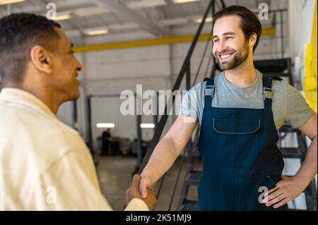 L'assistente amichevole dell'officina dell'automobile che saluta il suo cliente Foto Stock