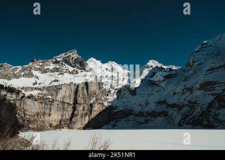 Lago di montagna ghiacciato di fronte alle alpi svizzere Foto Stock