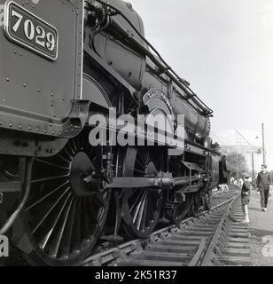 1970, storico, giovane ragazzo che guarda su una locomotiva a vapore presevata, n. 7029, Clun Castle, seduto su un binario, Bristol, Inghilterra, Regno Unito. La locomotiva, una locomotiva di classe 4073 della Great Western Railway, fu costruita nel 1950 presso la Swindon Railway Works. È stata ritirata dal servizio nel 1965. Foto Stock