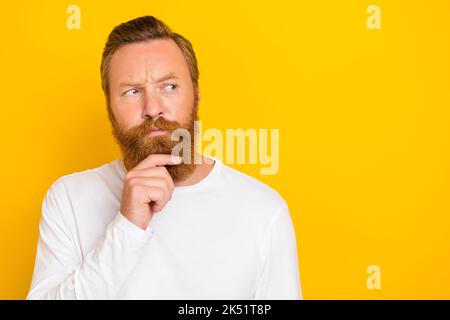 Ritratto fotografico di giovane uomo attraente tocco mento sguardo attento spazio vuoto indossare elegante vestito bianco isolato su sfondo giallo Foto Stock