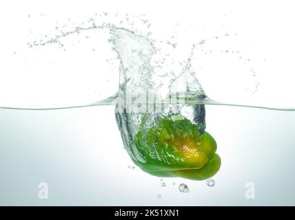 Il pepe verde si spruzzi in acqua. Vista laterale su sfondo bianco. Foto Stock
