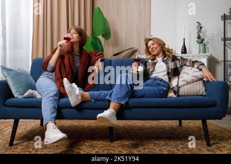 La donna e la figlia bevono vino e si divertono a casa Foto Stock