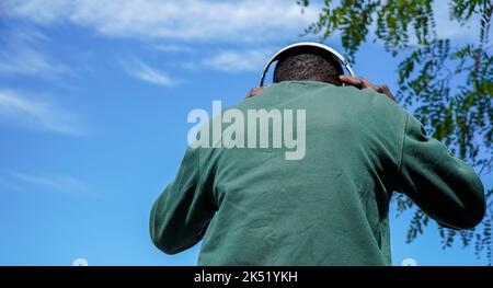 I giovani africani ascoltano musica da dietro con il cielo sullo sfondo Foto Stock