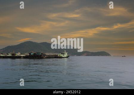 Barche da rimorchiatore e navi da carico ormeggiate nella baia di Koh Sichang, provincia di Chonburi in Thailandia, il cielo è tramonto del crepuscolo. Foto Stock