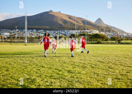 Ragazze, squadre di calcio o giochi di fitness sul campo d'erba in allenamento, allenamento o esercizio fisico per il gioco o gli obiettivi partita. Running, calcio o sport bambini Foto Stock