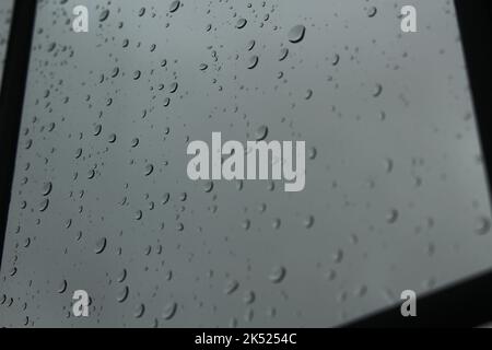 La pioggia cade su una finestra di vetro trasparente in una giornata di nebbia. Concetto per umore basso, depressione, fuori di specie, grigio, triste, giorni piovosi, bloccati all'interno Foto Stock