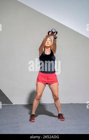 Vera giovane caucasica matura in un abbigliamento sportivo in palestra con kettlebell. Concetto di fitness. Foto Stock
