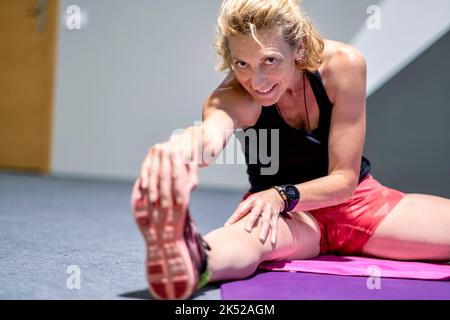 Vera giovane matura donna caucasica in un abbigliamento sportivo in palestra facendo stretching allenamento in palestra. Concetto di fitness. Foto Stock