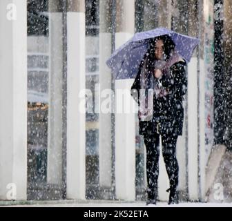 Belgrado, Serbia - 15 dicembre 2018: Una giovane donna sotto l'ombrello viola che cammina per la strada cittadina in una giornata nevosa Foto Stock