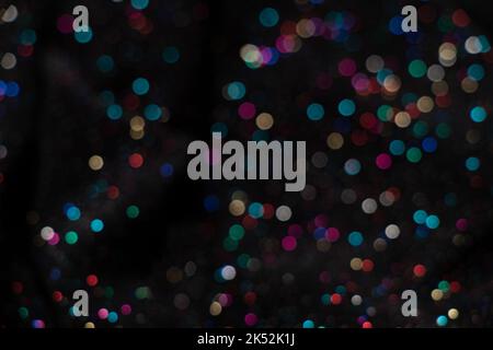 bokeh multicolore su sfondo nero, messa a fuoco sfocata, tessuto con brillantezza come sfondo Foto Stock