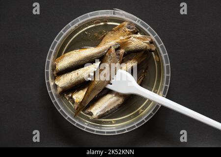 gli spratti in olio si trovano in una confezione di plastica su un fondo isolato, frutti di mare, pesce Foto Stock