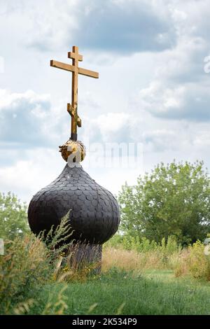 Vecchia punta di chirch russsiano con croce dorata separata portare giù su terreno e nuvole di erba Foto Stock