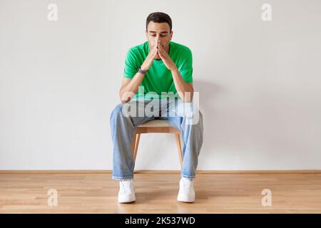 Ritratto di un uomo arabo penoso seduto sulla sedia a casa e pensando a qualcosa, soffrendo problemi di vita Foto Stock