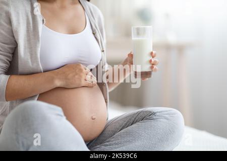 Donna incinta irriconoscibile che tiene un bicchiere di latte Foto Stock