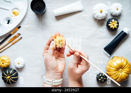 Mani femminili con zucche da pittura. Idee creative di pittura della zucca per Halloween e il Ringraziamento per gli adulti. Semplice Easy Pumpkin decorazione kit Foto Stock