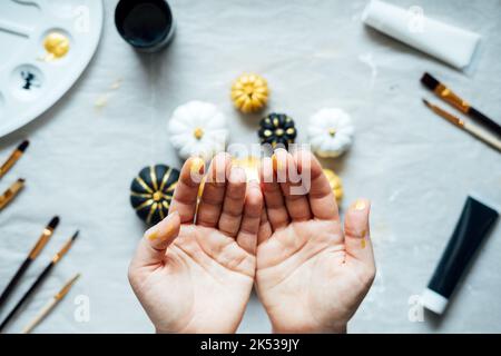 Mani femminili con zucche da pittura. Idee creative di pittura della zucca per Halloween e il Ringraziamento per gli adulti. Semplice Easy Pumpkin decorazione kit Foto Stock