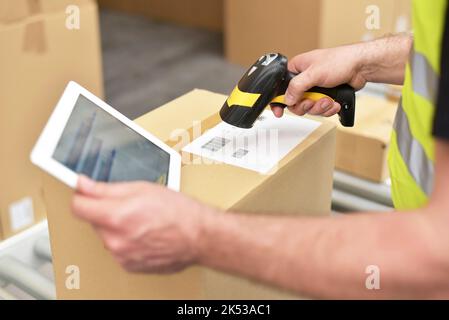 addetti al magazzino che eseguono la scansione dei pacchi per la spedizione al dettaglio e per il trasporto Foto Stock