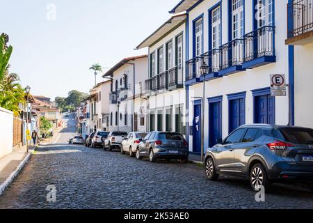 Strada acciottolata con edifici coloniali e auto parcheggiate a Sabará, Minas Gerais, Brasile. Foto Stock