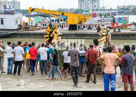 Il lavoro di immersione di Durga idol è in corso a Ganga Ghat di Kolkata. Il grande idolo viene portato al fiume da una gru. Foto Stock