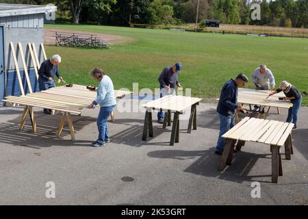 St. Johnsville, Montgomery County, New York: Volontari dipingono stecche di legno durante la riparazione della tribuna al campo di palla comunità. Foto Stock