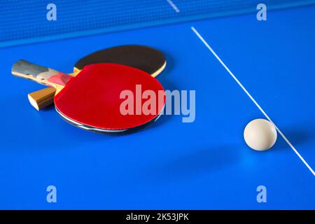 Giochi sportivi a Ping Pong. Racchette per ping pong e una palla sul tavolo blu Foto Stock