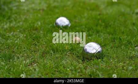 Primo piano di palle di bocce d'acciaio su un prato verde. Messa a fuoco selettiva. Palle di bocce in acciaio cromato giacciono sull'erba. Gioca nel tuo garde Foto Stock