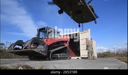 I membri del 202nd Rapid Engineer Deployable Heavy Operational Repair Squadron Engineers (RED HORSE) Squadron, Florida Air National Guard, ricevono attrezzature a St. James City, Pine Island, Florida in risposta all'uragano Ian, 3 ottobre 2022. Ciò segna la prima volta nella storia delle unità che il personale e le attrezzature sono stati sollevati in un'area di disastro dall'esercito. Lo squadrone A CAVALLI ROSSI del 202nd, di stanza a Camp Blanding, Florida, è un team specializzato e altamente mobile di ingegneria civile composto da Florida Air National Guardsmen che fornisce capacità di risposta rapida per più mondo Foto Stock