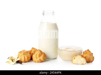 Deliziose eclarie, crema e bottiglia di latte su sfondo bianco Foto Stock