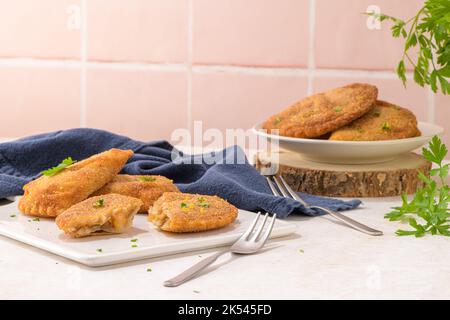 Polpettine di carne e foglie di prezzemolo su piatti di ceramica bianca in una cucina da banco. Foto Stock