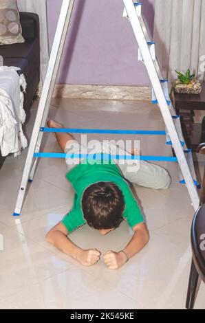 Ritratto di un bambino che gioca al piano di sotto su una scala. Abilità a casa. Salvador, Bahia, Brasile. Foto Stock