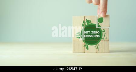 Concetto di emissioni zero nette. Carbonio neutro. Strategia a lungo termine neutra per il clima. Sviluppo sostenibile delle imprese. Business ecologico. Mettere a mano il cubo di legno Foto Stock