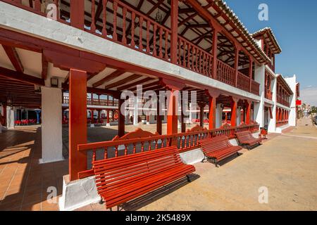Struttura in legno dipinta di rosso e mattoni imbiancati in Plaza de Consuegra. Foto Stock