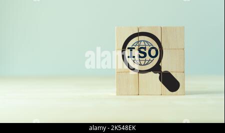 Concetto di certificazione del controllo di qualità degli standard ISO. Garanzia e garanzia di qualità. Cubi di legno con ISO, globo intelligente, icone lente di ingrandimento sul dorso grigio Foto Stock