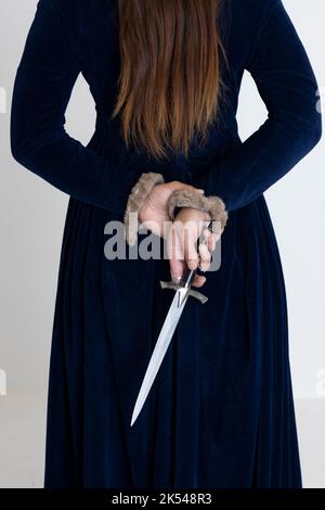 Una donna medievale o fantasy che indossa un abito di velluto blu e tiene una spada Foto Stock