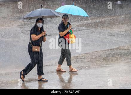 SAMUT PRAKAN, THAILANDIA, ottobre 03 2022, due donne con ombrelloni stanno camminando per la strada sotto la pioggia Foto Stock