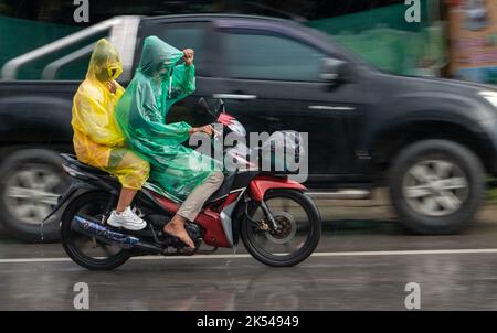 Coppia in impermeabile guidare in pioggia, Thailandia Foto Stock