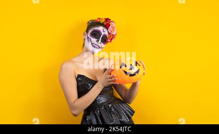 Catrina messicana, ritratto di una giovane donna ispanica in possesso di una zucca calaverita di plastica per il giorno della festa dei morti o di Halloween in Messico America Latina Foto Stock