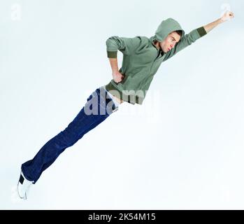 HES un supereroe aereo. Un giovane che vola nella posa del supereroe. Foto Stock