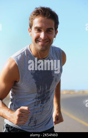 Amo questi scherzi di mattina. Bel giovane atleta sorridente alla macchina fotografica mentre fa jogging. Foto Stock