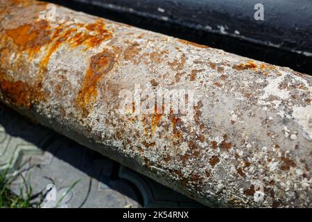 un tubo arrugginito di metallo grande si trova su calcestruzzo Foto Stock