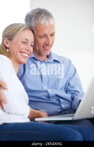 Fare i programmi di festa. Una giovane coppia che guarda contenuti mentre condividono un notebook. Foto Stock