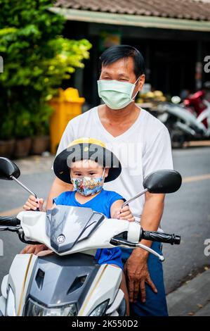 Un piccolo ragazzo tailandese fa un giro sulla parte anteriore di una moto a Bangkok Thailandia. Foto Stock